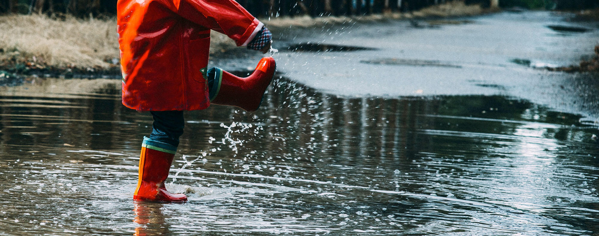 Child with welly boots playing in puddles