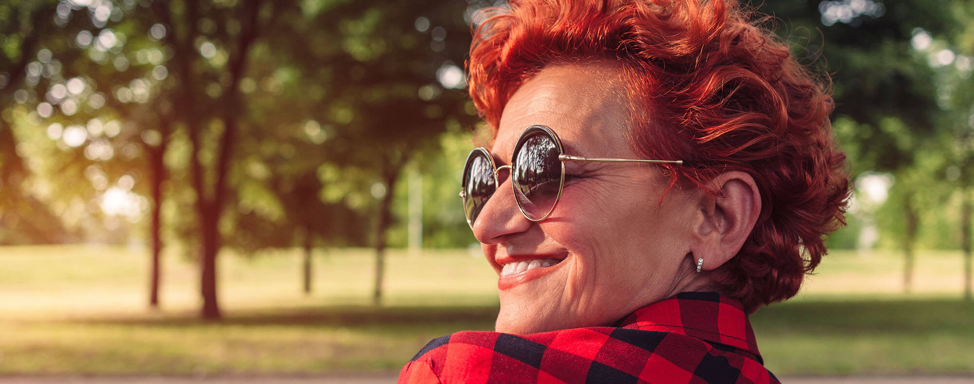 Smiling mature woman wearing sunglasses in a sunny park